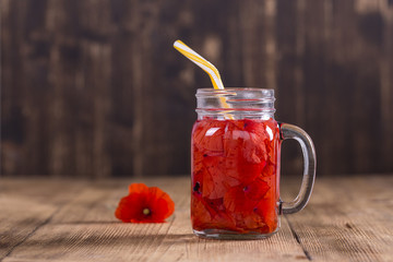 Red poppy flower tea drink in glass mug on wooden background. Concept of healthy eating