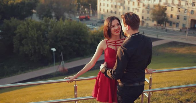 Romantic couple stand at a parapet on a background of city houses