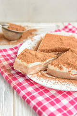 Homemade layered cottage cheese souffle dessert with cocoa on white wooden table