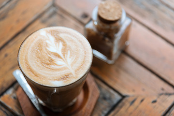 Latte coffee in the traditional glass of Thailand and placed on the wooden table in selective focus.