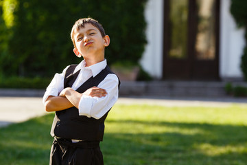 Cheerful boy in fashionable suit on green grass
