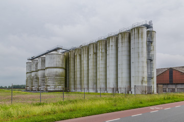 Row of old weathered tall tanks from a n old  abandoned actory