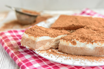 Homemade layered cottage cheese souffle dessert with cocoa on white wooden table