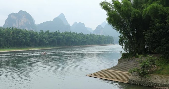 Scenic view of sailing boat along the Li River among green woods and karst mountains at Yangshuo County of Guilin, China. Yangshuo is a popular tourist destination of Asia.
