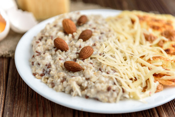 Oatmeal with omelette and cheese on dark wooden table. Healthy breakfast.