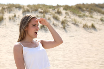 Fototapeta na wymiar Hübsche junge Frau an einem Strand schaut erstaunt in eine Richtung