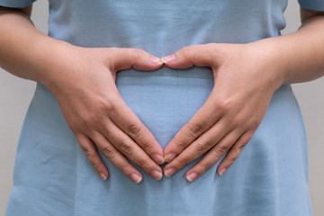 isolated  pregnant woman with hands in heart shape gesture