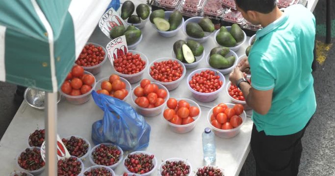 Consumer at a fruit market stall selecting and buying fruit