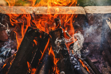 Smoke and flames rising from burning firewood on a sunny summer day