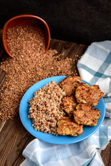 Chicken cutlets with buckwheat porridge on blue plate on wooden table.