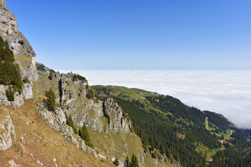 View from Aggenstein mountain (Allgaeu Alps) to the summit station of "Breitenbergbahn" and a sea of clouds above the alpine upland. Bavaria, Germany