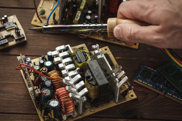 Master soldering radio components, repairing a computer with a hand in the frame