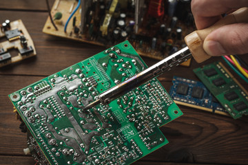 Soldering the electric wiring by the master, hand in the frame. Computer repair.