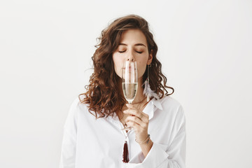 Studio portrait of beautiful sensual caucasian brunette smelling white wine while holding glass...