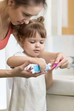 Mom Puts Toothpaste On A Child Brush, Brushing Teeth