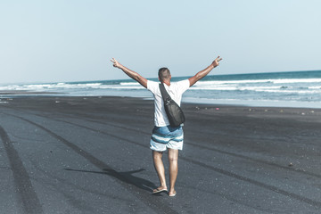 Man on the black sand beach. Bali island.
