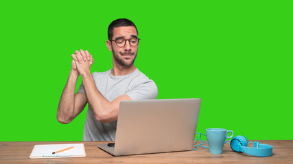 Confident young man sitting at his desk with a gesture of teamwork - Green background