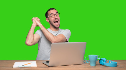 Happy young man sitting at his desk with a gesture of winner - Green background