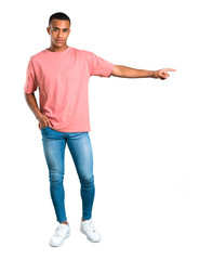 Standing young african american man pointing finger to the side and presenting a product on isolated white background
