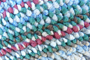 Fototapeta na wymiar motley colored fabric boucle mohair cloth knitwear carpet close-up woolen thread scarf blue red gray green