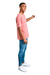 Standing young african american man pointing back with the index finger presenting a product on isolated white background