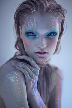 Portrait of alien woman with glitter make up looking at camera