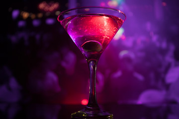 glass with martini with olive inside. Close up view of glass with club drink on dark foggy toned background. Club drink concept