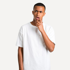 Young african american man having doubts and with confuse face expression while looking up. Questioning an idea on isolated background