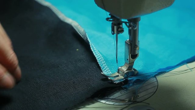 Close-up of woman's hands sewing an overlock at sewing machine.