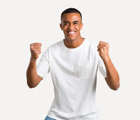 Young african american man celebrating a victory and happy for having won a prize on isolated background