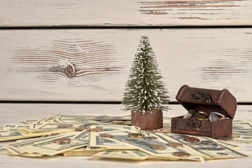 Christmas and finance concept. Pile of money, moneybox chest and tiny christmas tree.