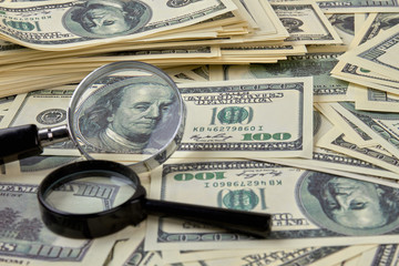 Heap of dollars and magnifiers. Concept close-up money dollars and magnifiers background.