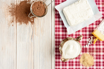 Fototapeta na wymiar Ingredients for homemade cottage cheese souffle dessert with cocoa on white wooden table. Recipe of healthy dessert.