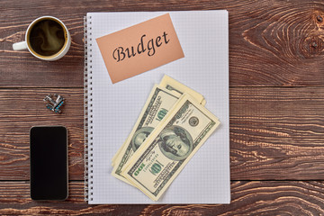 Naklejka premium Accounting notepad, money and accessoires. Blank notepad, money, smartphone and cup of coffee.
