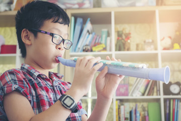 Boy playing the clarinet, trumpet at home, blowing a sweet flute, musicology background, music skills learning and education. © tongpatong