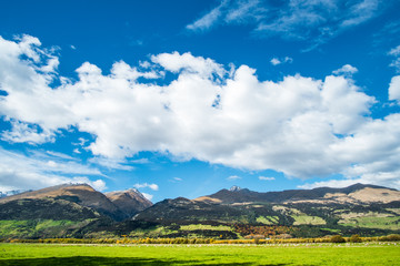 Beautiful scene of the green grassland and alps mountain with cloudy sky.