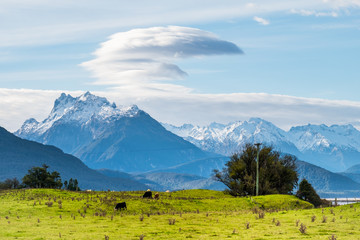 Beautiful scene of the green grassland and alps mountain with cloudy sky.