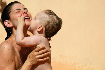 Mama spielt mit ihrem Baby ausgelassen im Wasser unter der Sonne