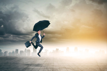 Asian businesswoman jumps with umbrella