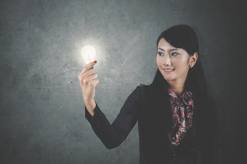 Beautiful businesswoman holding a bright bulb