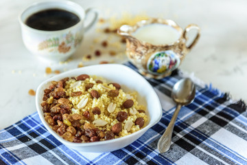Millet porridge with milk, raisins and peanuts on light background. Healthy breakfast.