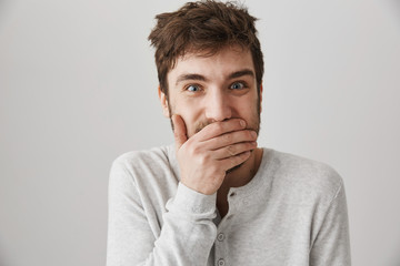 Man got insane. Portrait of weird crazy guy with messy haircut laughing and looking with strange expression at camera, standing over gray background, posing like psychopath. Male lost his mind