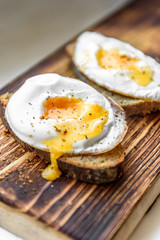 Healthy sandwich of fried egg with rye bread on wooden cutting board on white background.