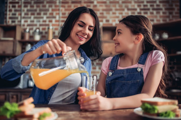 mother pouring orange juice into the glass