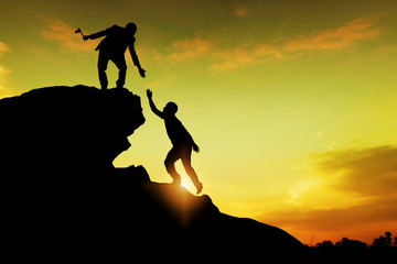 Assistance, teamwork and achievement concept. silhouette of man helping friend to success together