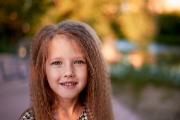 Fototapeta premium The baby is 4 years old, with blue eyes and small curls. Children's enjoyment of life and adventures. Warm Golden sunset light.Smiles