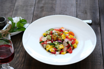 flowers, wine and serving of salad from vegetables on old wooden table