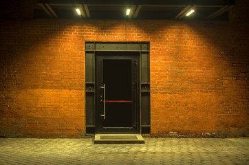 Night view. Industrial building. Large doors in a red brick building. The entrance to the warehouse. Facade