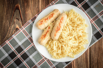 Diet healthy homemade grilled chicken sausage with pasta and cheese on dark wooden background. Healthy food for dinner.