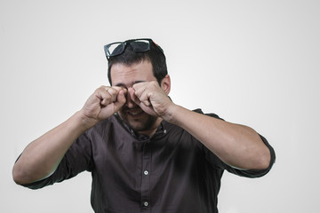 man scratching his eyes with the glasses removed